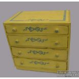 A vintage painted small chest of drawers, four long, bun handles, painted in yellow with blue bows,