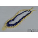 A graduated row of 38 Lapis Lazuli beads, c1920, and a 1920's bone or marine ivory bead necklace (