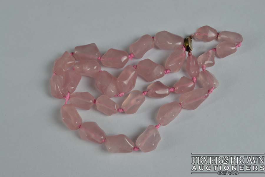 A Chinese slightly graduated row of 29 baroque shaped rose quartz beads on a silver gilt clasp