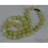 A Chinese slightly graduated row of 39 12mm to 15mm pale whitish green coloured jade beads to a