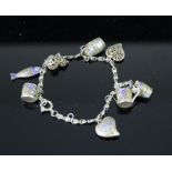 A silver gilt and enamel filigree charm bracelet includes cup, fish, heart, bucket and watering