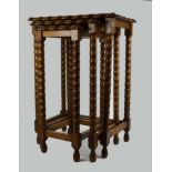 A nest of three oak tables, scalloped edged tops, sitting on long bobbin turned legs, with plain