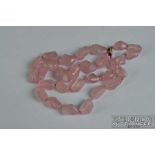 A Chinese slightly graduated row of 29 baroque shaped rose quartz beads on a silver gilt clasp