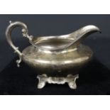 A silver cream jug on four 'C' scroll volute feet with foliate scroll handle, London 1834, makers