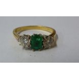 An emerald and diamond three stone ring, c1960, the rectangular shaped emerald flanked either side