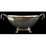 A large silver centrepiece bowl, of fluted oval form with two protruding ring handles and on four