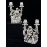 A pair of Volskadt ivorine porcelain candelabra figures, modelled as a female goatherd; and a male