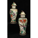 A pair of Chinese pottery vases and covers, painted in famille rose colours with warriors on a