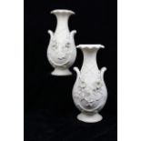 A pair of biscuit porcelain vases, in the white, ovoid with foliated trumpet neck encrusted with