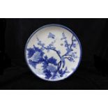 A Japanese Arita porcelain charger, painted in blue and white with birds amid flowering peonies,