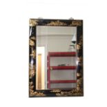 A Chinese black lacquered framed mirror, decorated with gilding with pagodas in landscapes, bevelled