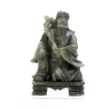 A variegated spinach green Chinese soapstone figure of an immortal holding a sceptre across his