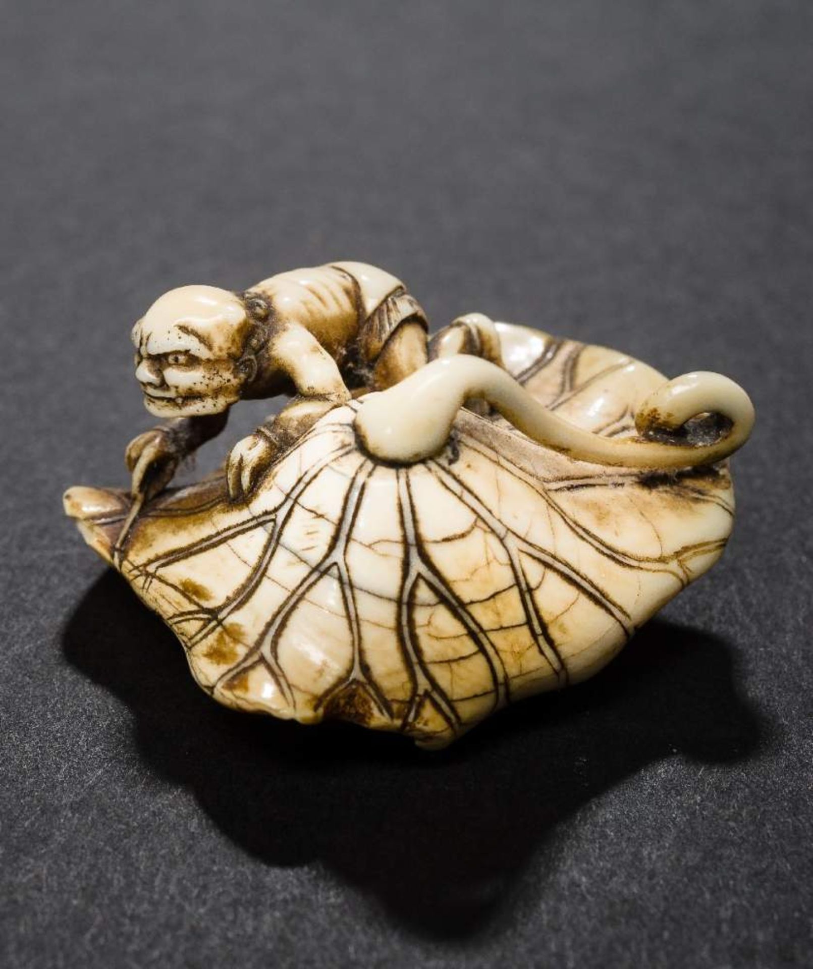 EIRAKU: EIN ONI AUF LOTUSBLATTNetsuke, Elfenbein. Japan, 1. H. 19. Jh.Sehr gute alte Arbeit, aus