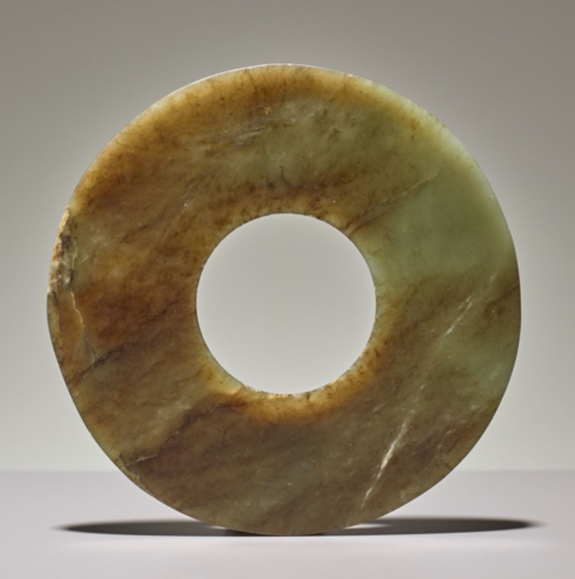 DISC IN SEMI-TRANSLUCENT JADEJade. China, Late Neolithic period, Qijia culture, c.2200-1900