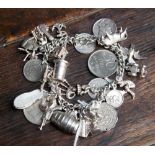 A silver charm bracelet containing a large quantity of assorted items