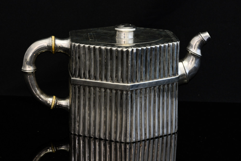 An Aesthetic Movement silver teapot, hexagonal section, each side with strapped dowel fence design,