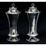 A pair of Edwardian silver pepperettes, of waisted conical form, with angular terminals,