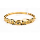 A 9 ct gold bangle with the flower designs set with sapphires, 13.9 grms gross approx.