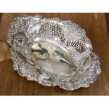 An Edwardian pierced dish raised on ball feet with repouse fruit and scroll decoration,