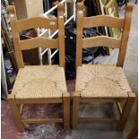 A pair of contemporary solid beech ladder-back chairs, fitted with drop-in rush seats,