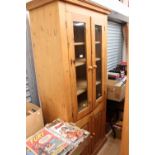 A contemporary pine bookcase, having two glazed doors opening to reveal three shelves,