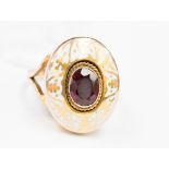 A garnet and white enamel gold ring,