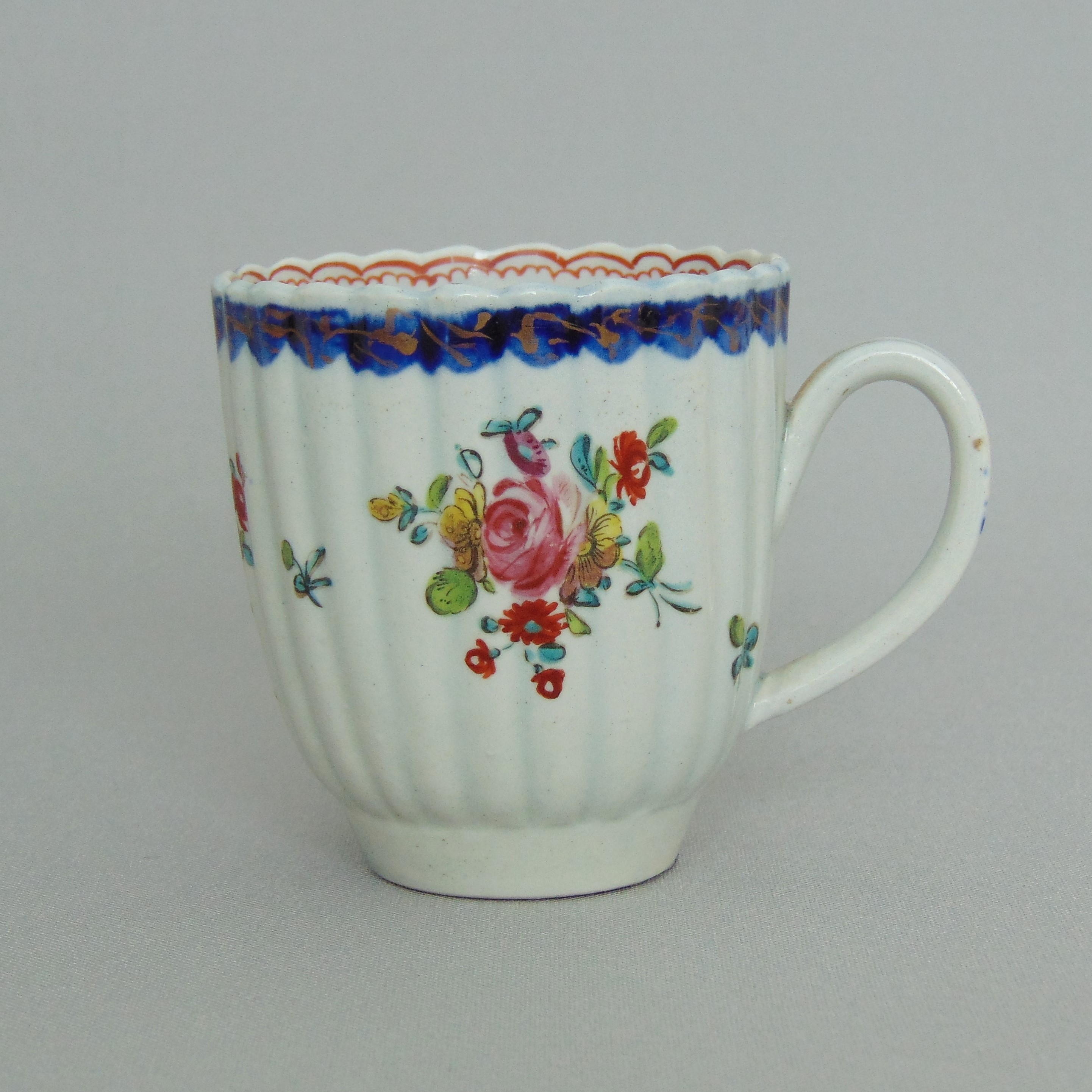 A Liverpool James Pennington ribbed polychrome coffee cup, decorated with painted flower sprays,