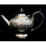 A George III silver bullet shaped teapot, the body decorated with embossed rococo scrolls,