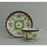 A Worcester tea cup and saucer, decorated with flowers within a green and blue border, circa 1775,