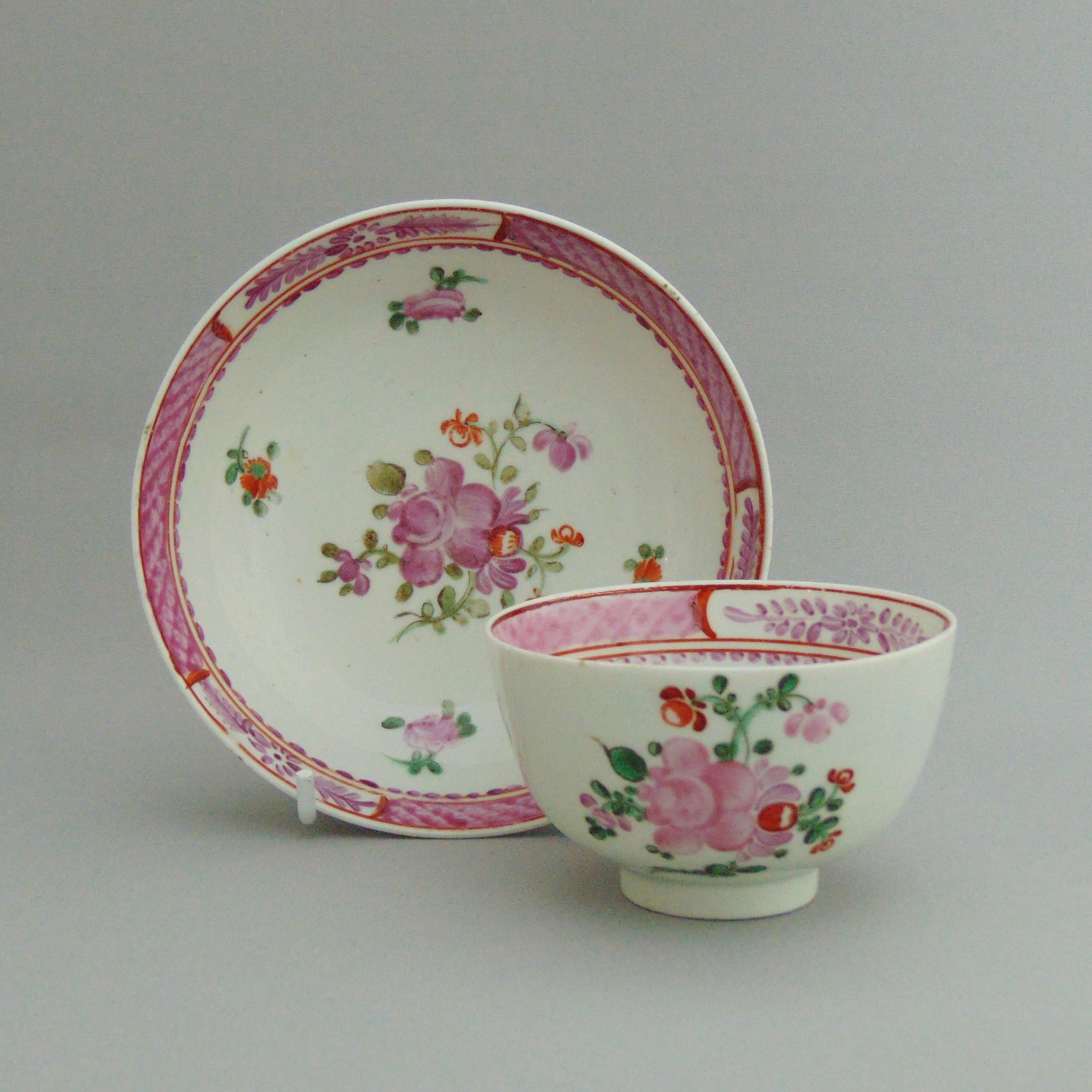 A Lowestoft polychrome tea bowl and saucer, Chinese Export Style, pink borders with floral sprays,