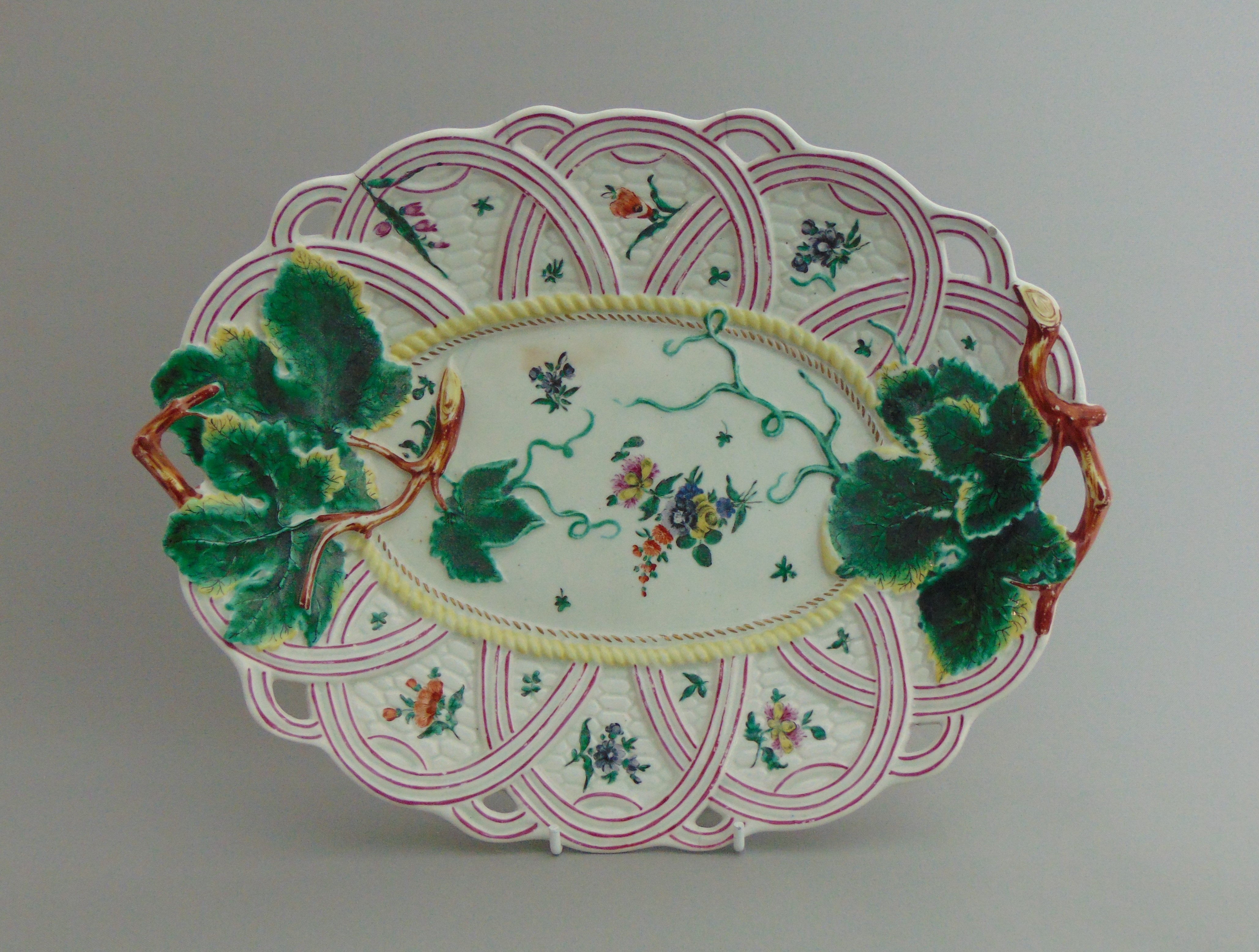 A Worcester basket moulded twig handle dish, with applied vine leaves and pink basket weave border,