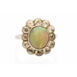 An opal and diamond oval cluster ring, the central opal 11mm by 9mm,