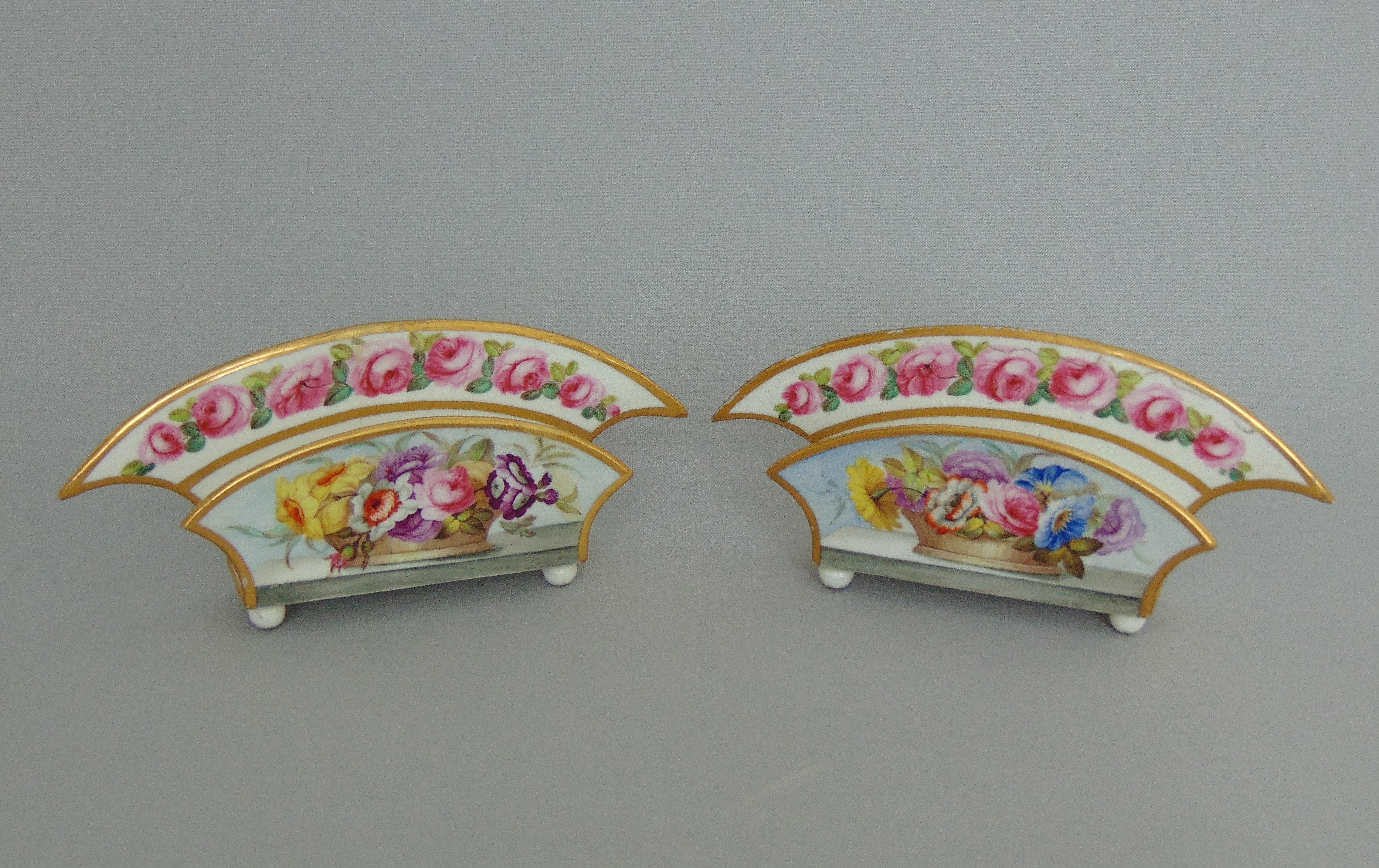 A small pair of Derby letter racks, highly decorated with floral sprays and a Rose border rim,