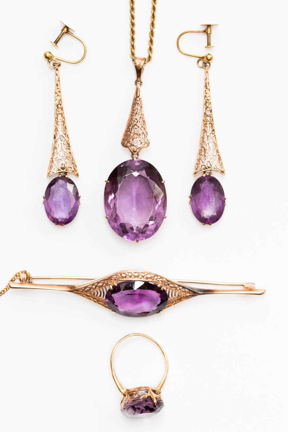 An Edwardian boxed suite of amethyst and yellow metal jewellery, comprising pendant,