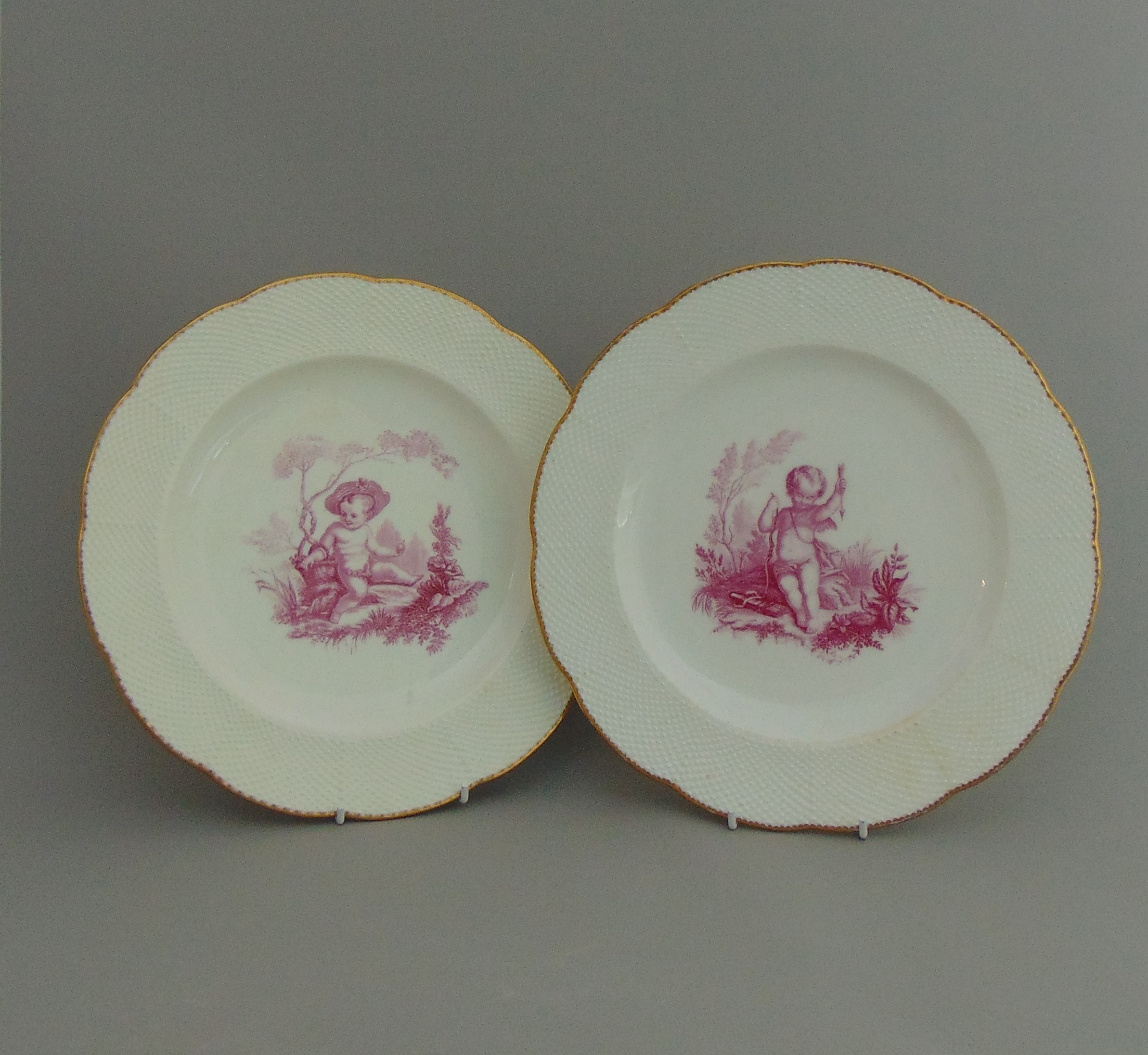 A pair of Minton plates, centre decorated in purple with Putti, circa 19th Century,