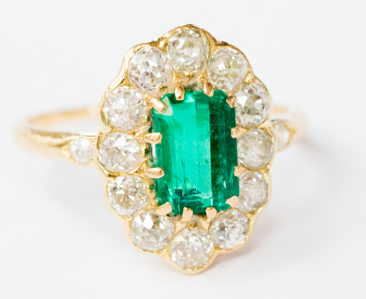 An emerald and diamond cluster yellow metal ring,