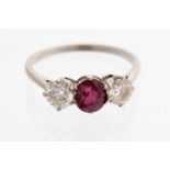 A ruby and diamond three stone platinum ring, the oval ruby of a good colour,