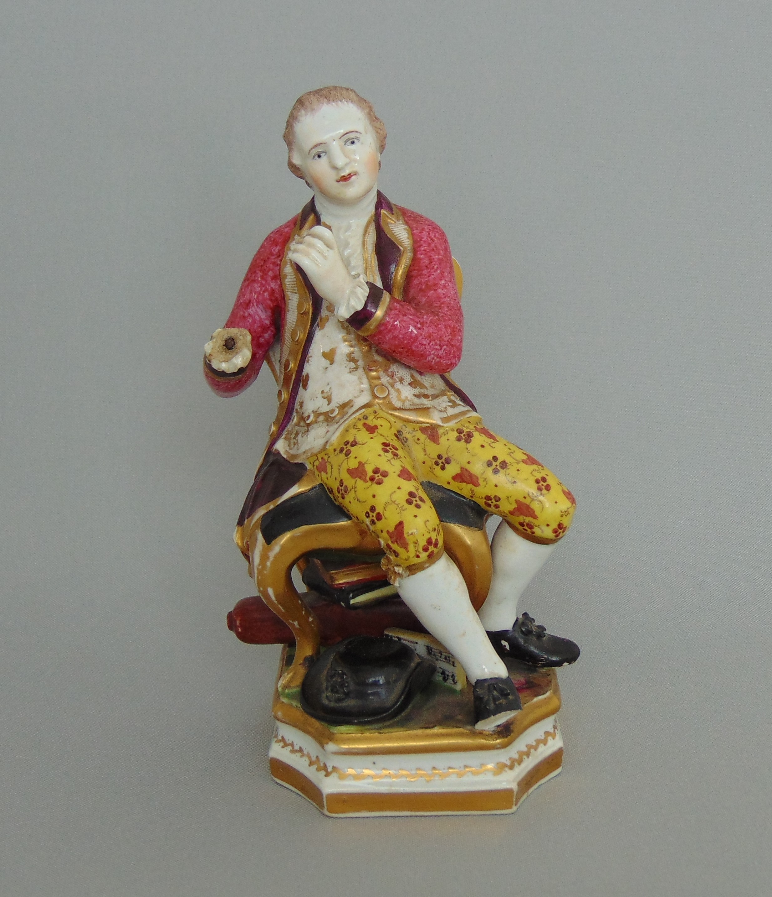 A Derby figure of a seated musician dressed in bright attire, circa 1815,