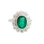 An emerald and diamond oval cluster white gold ring,