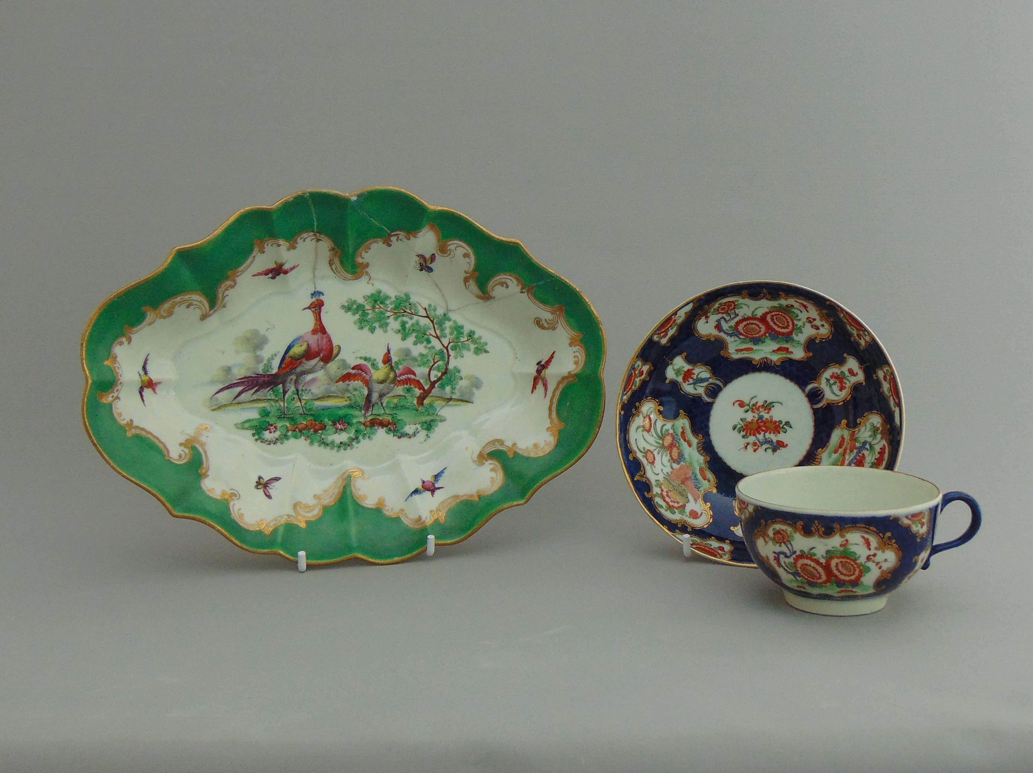 A Worcester green ground dish with painted birds in the centre and a Worcester blue scale tea cup
