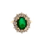 An emerald and diamond cluster ring, the centre oval emerald approx 10 x 7.