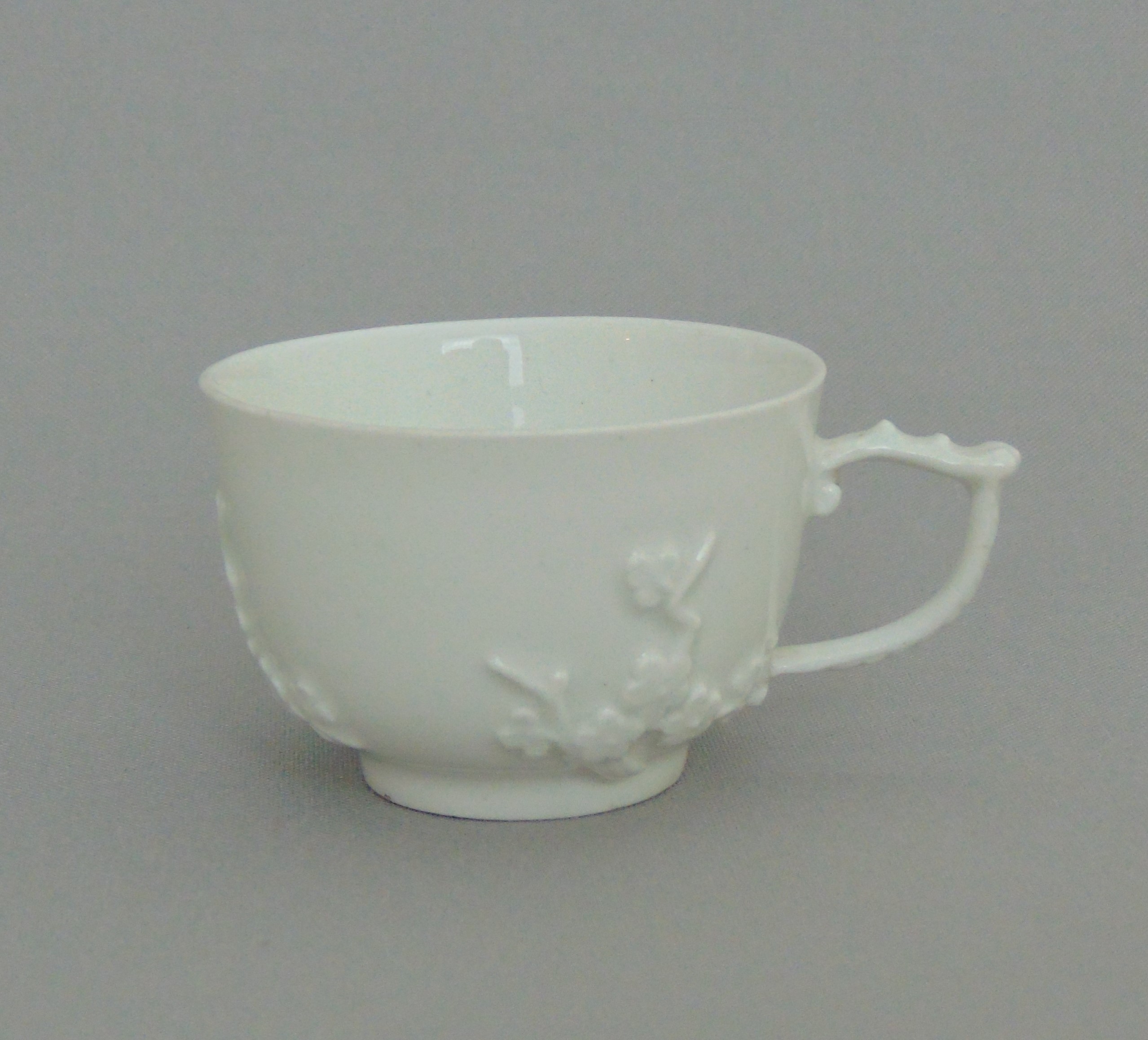 A Meissen small white tea cup, with applied sprigs and ornate handle, circa 1745, 4cm high,