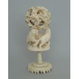 A small Chinese antique ivory puzzle ball on a carved lion stand, circa 1900,