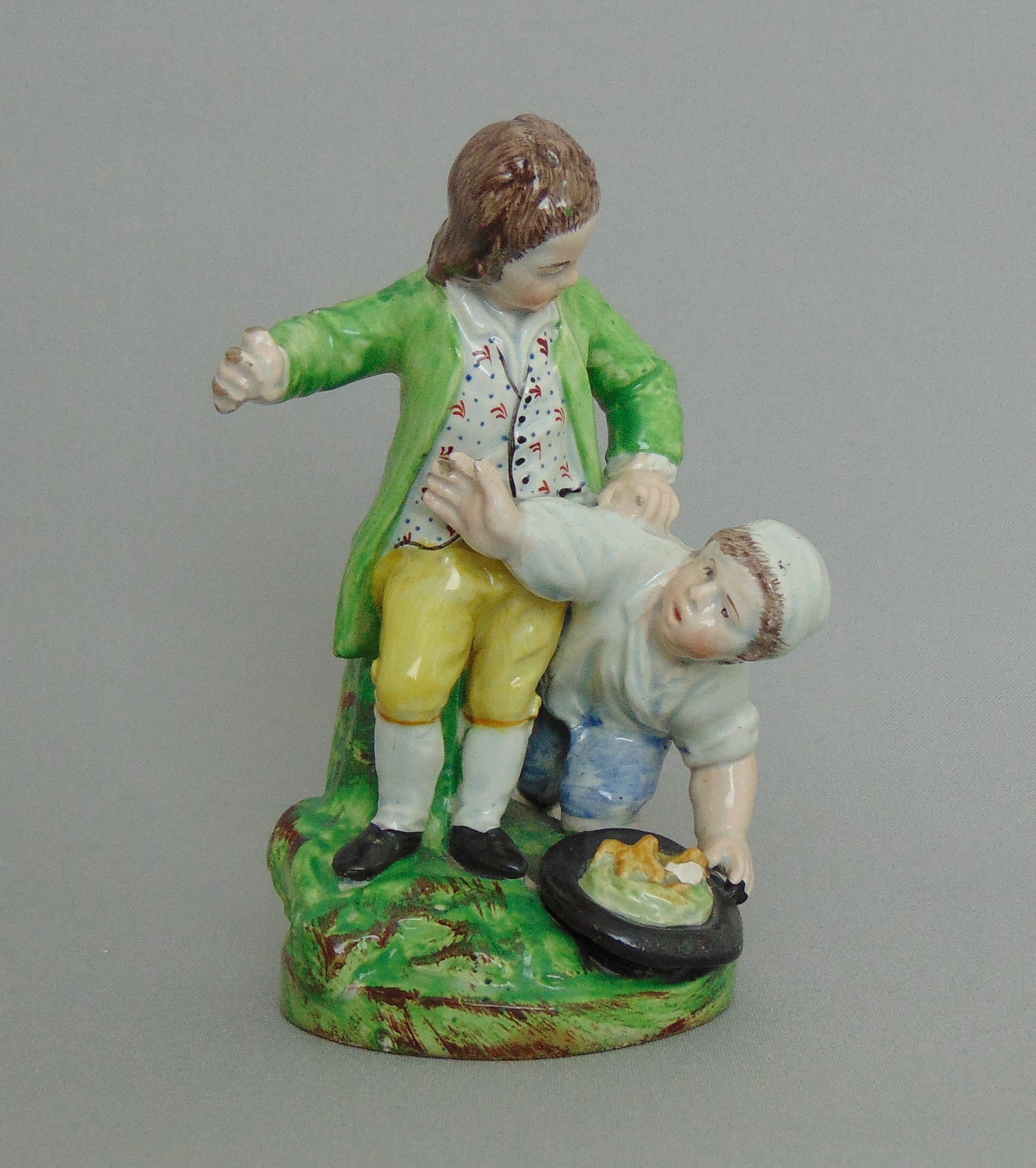 A Staffordshire pearlware group 'Bird Nesting', two boys on a grassy mound with a birds nest,