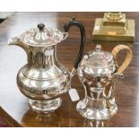 A George V silver hot water pot of baluster form on a circular foot with leaf scroll decoration