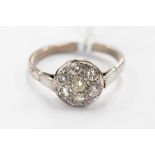 A platinum and diamond cluster ring, illusion set seven diamonds, the shank stamped 18ct,