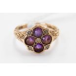 A 9 ct gold dress ring set with four amethyst and small seed pearls between scrollwork patterned