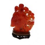 A Chinese red agate carving on a hardwood plinth,