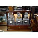 An oak tantalus, with three cut glass decanters, one having silver brandy label,