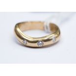 A three stone diamond 9ct yellow gold wavy edge ring, gypsy set graduating diamonds,